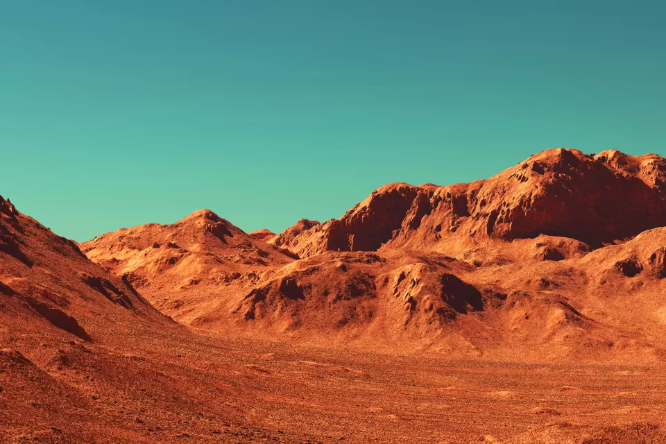 Barren rocky landscape against teal sky.